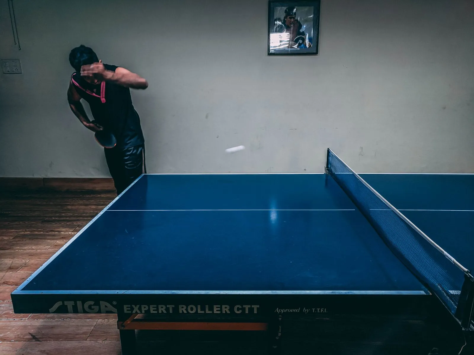 A player mid-serve during a live table tennis rally