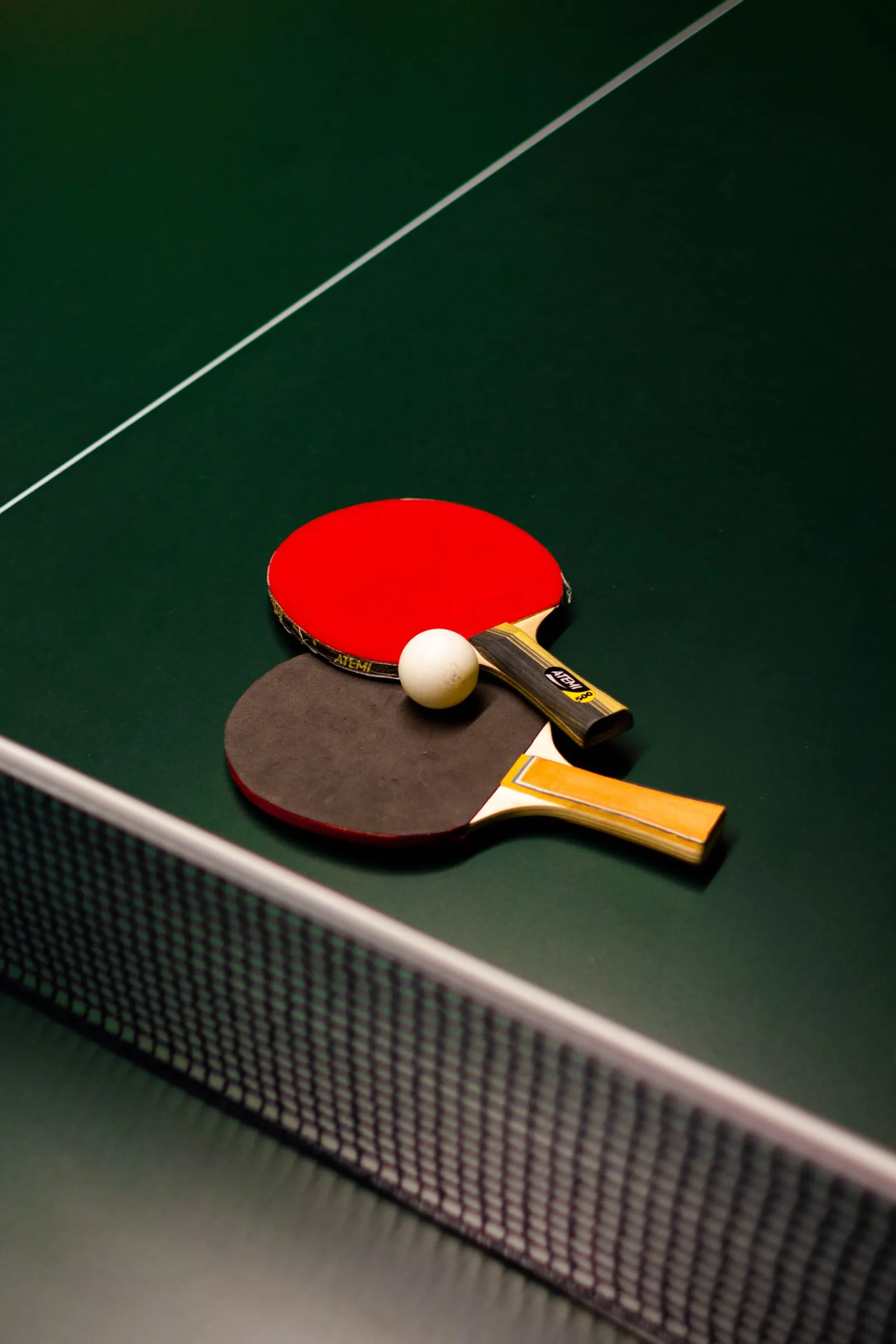 Two table tennis bats and a ball crossed on a table